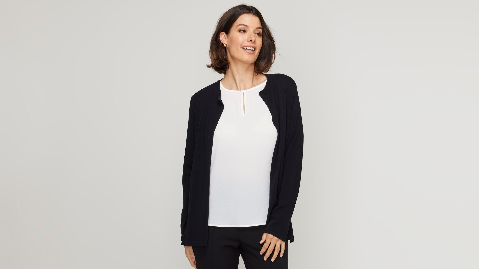 A basic white blouse and black cardigan are staples of a capsule wardrobe