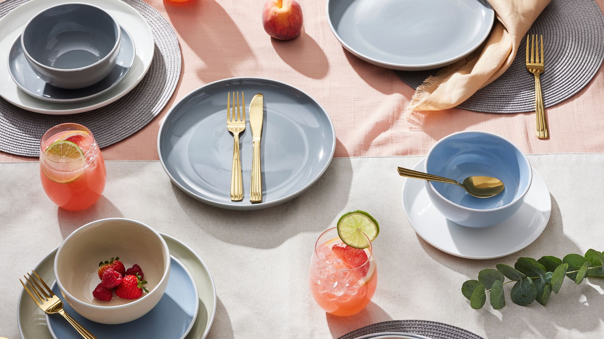 Dining set-up with gold cutlery and a mix of baby blue, sage green and white tableware